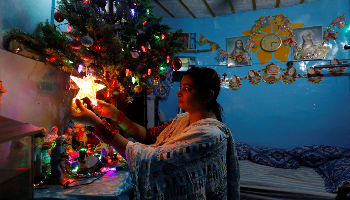 Sumaira Junaid, 28, poses as she decorates her Christmas tree with an illuminated star, ahead of the Christmas celebrations, in Karachi, Pakistan December 23, 2021. — Reuters.