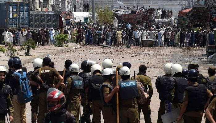 Policemen stand guard as supporters of Tehreek-e-Labbaik Pakistan take part in a protest while blocking a street in Lahore, on April 18, 2021. — AFP