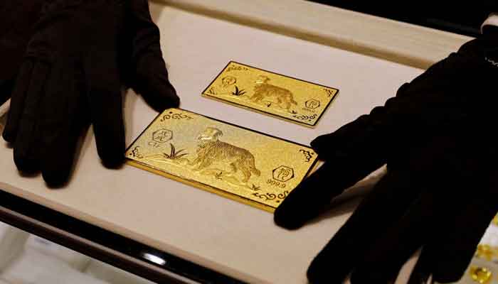 A salesperson arranges 24K gold bars engraved with dogs at Chow Tai Fook Jewellery store ahead of the Lunar Year of the Dog in Hong Kong, China December 14, 2017.— Reuters/File