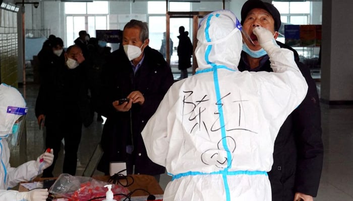 A medical worker in protective suit collects a swab sample from a man for nucleic acid testing at a residential compound, during another round of mass testing following the coronavirus disease (COVID-19) outbreak in Xian, Shaanxi province, China December 27, 2021. — Reuters/File