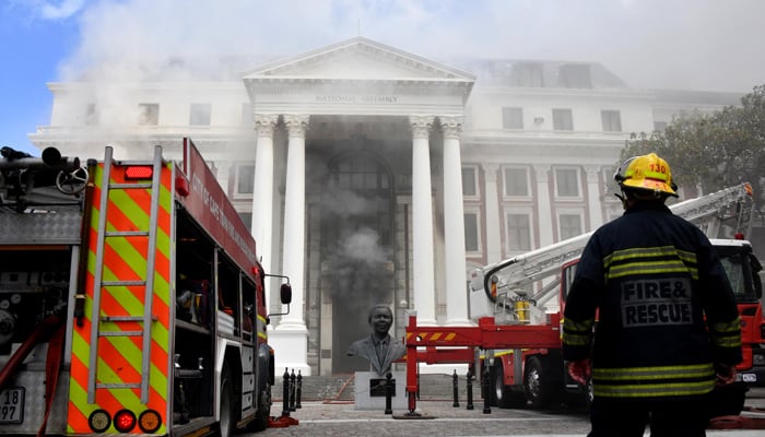 A firefighter looks at the smoke rising after a fire broke out in the Parliament in Cape Town, South Africa, January 2, 2022. — Elmond Jiyane/GCIS/Handout via Reuters