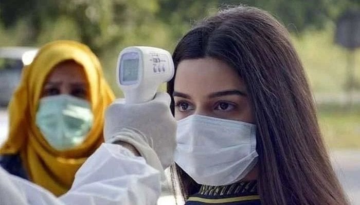 A paramedic checks temperature of a woman with a temperature gun. Photo: Geo.tv/file