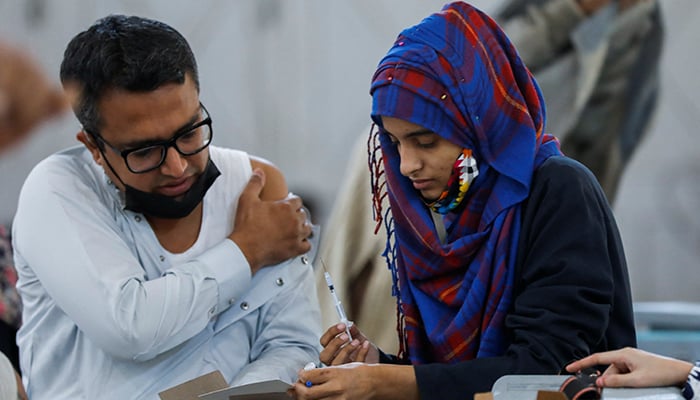 A healthcare worker checks a record card of a man before administering a dose of the coronavirus (COVID-19) vaccine at a vaccination centre in Karachi, Pakistan, January 4, 2022. — Reuters