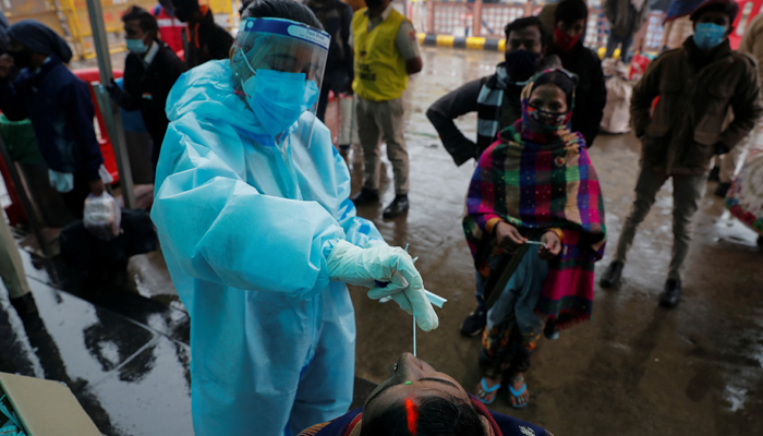A healthcare worker collects a coronavirus disease (COVID-19) test swab sample from a woman as others wait, amidst the spread of the disease, at a railway station in New Delhi, India, January 5, 2022. — Reuters/Adnan Abidi