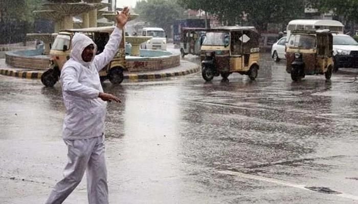 A traffic cop regulates traffic on a road amid downpour. Photo: Geo.tv/files