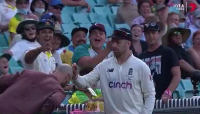 Spinner Jack Leach signs a fans bald head during the games intermission. Screen Grab from a Twitter video.