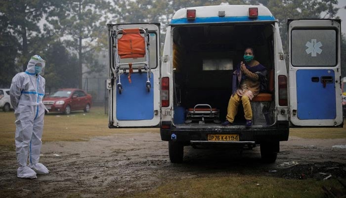 A medical worker wearing personal protective equipment (PPE) stands next to a patient suffering from coronavirus disease (COVID-19), sits inside an ambulance, after she arrived to a care centre at an indoor sports complex, amidst the spread of the disease, in New Delhi, India, January 5, 2022. — Reuters/File