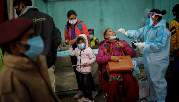 A healthcare worker collects a coronavirus disease (COVID-19) test swab sample from a woman amidst the spread of the disease, at a railway station in New Delhi, India, January 5, 2022. — Reuters/File