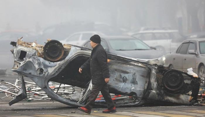 A man walks past a car that was burned during the protests triggered by fuel price increase in Almaty, Kazakhstan January 6, 2022.