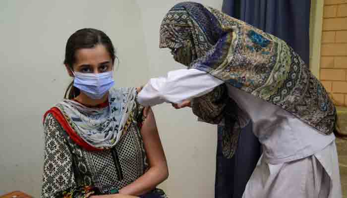 A lady health worker administering vaccine to a female. — Unicef