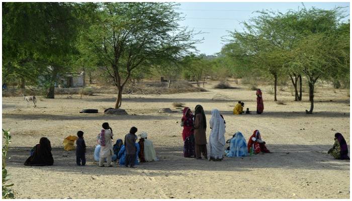 Pakistani villagers sit under trees on a hot summer day at Islamkot in Tharparkar district in Sindh province on May 22, 2018. — AFP/File