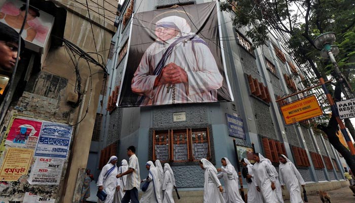 Nuns belonging to the global Missionaries of Charity, walk past a large banner of Mother Teresa ahead of her canonisation ceremony, in Kolkata, India September 3, 2016.— Reuters/File