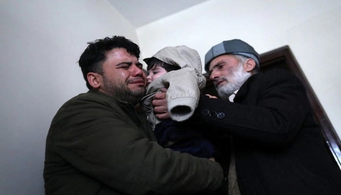 Hamid Safi, a 29-year-old taxi driver who had found baby Sohail Ahmadi in the airport, cries as he hands over Sohail to his grandfather Mohammad Qasem Razawi in Kabul, Afghanistan, January 8, 2022. Photo: Reuters