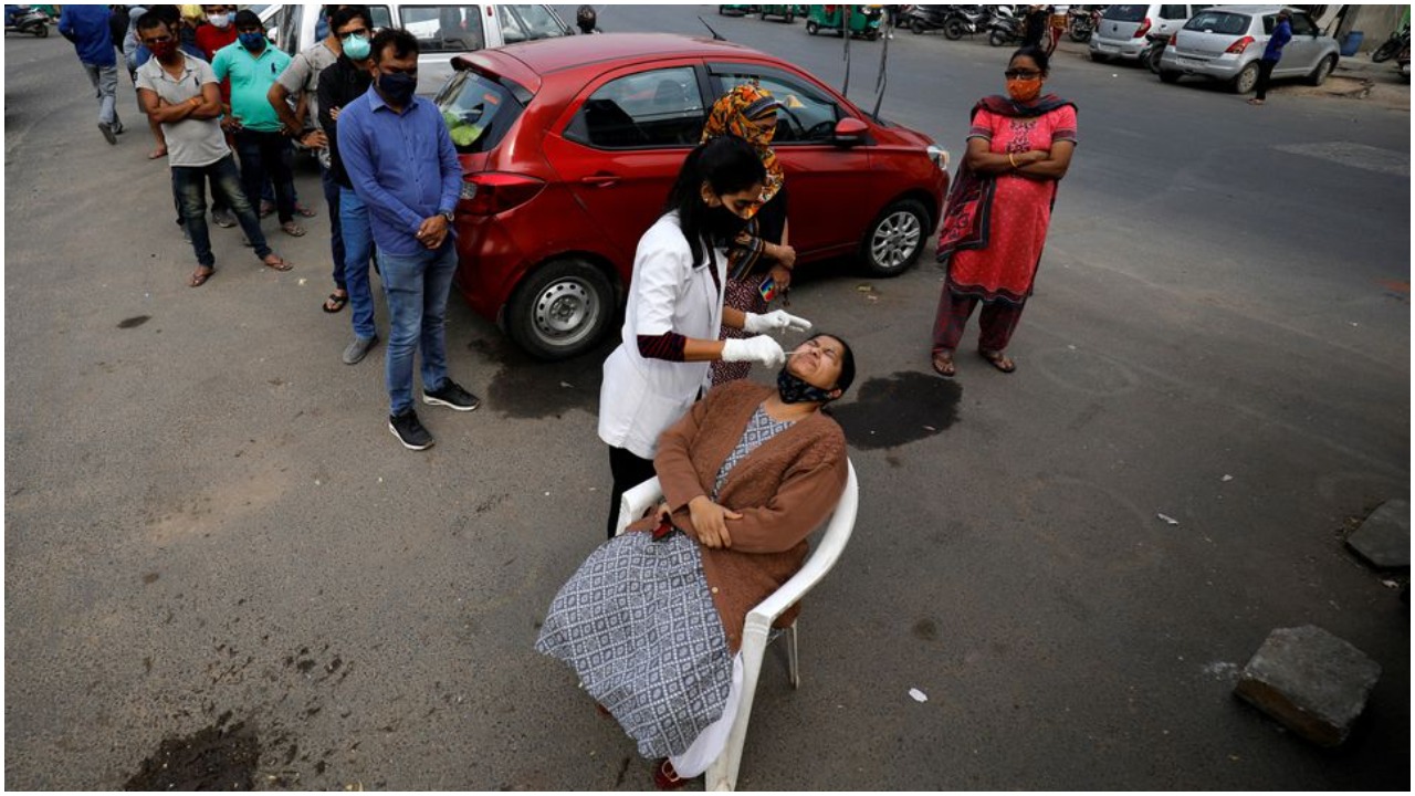 A healthcare worker collects a swab sample from a woman as others wait for their turn during a rapid antigen testing drive for the coronavirus disease (COVID-19) at a roadside in Ahmedabad, India, January 5, 2022. Photo: REUTERS