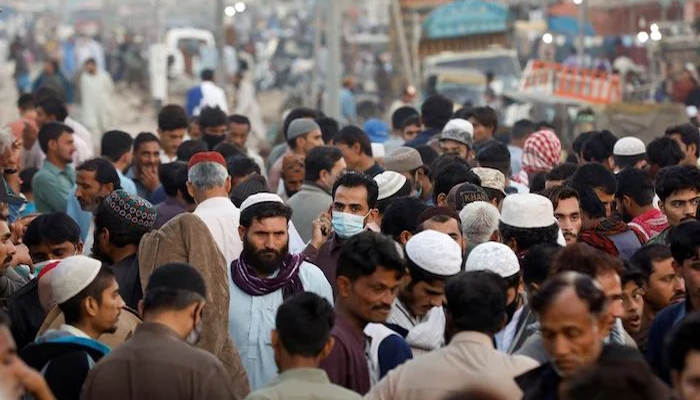 A man wearing a protective mask walks through a crowd of people along a makeshift market as the outbreak of the coronavirus disease (COVID-19) continues in Karachi. — Reuters
