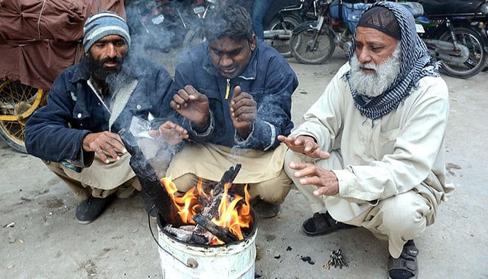 Citizens warm their hands around a makeshift fire in Karachi. — APP