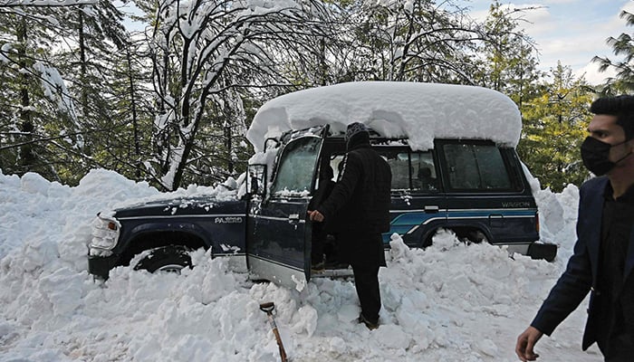 A tourist removes snow from his vehicle stucked on a road following a blizzard that started on January 7 which led to visitors being trapped in vehicles along the roads to the resort hill town of Murree, some 70 Kms northeast of Islamabad on January 9, 2022. — AFP/File