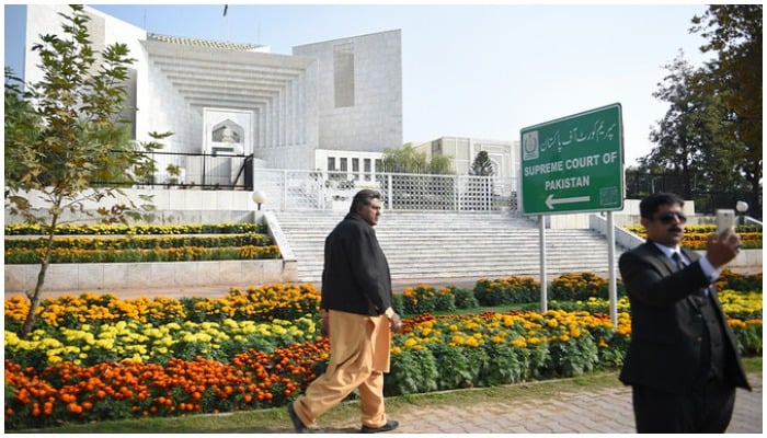 A Pakistani lawyer (R) uses his mobile phone in front of the Supreme Court building in Islamabad on November 28, 2019.— AFP/File