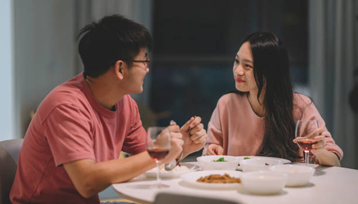 A Chinese couple having dinner at home with red wine and Chinese cuisine. — iStock photo