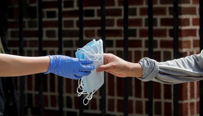 A woman receives protective face masks while she waits in line at a food bank at St. Bartholomew Church, during the outbreak of the coronavirus disease (COVID-19) in the Elmhurst section of Queens, New York City, New York, U.S., May 15, 2020. Photo: Reuters