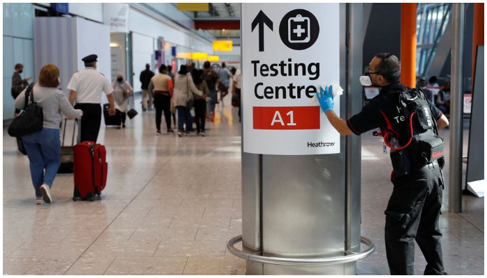 A worker sanitises a sign at the International arrivals area of Terminal 5 in Londons Heathrow Airport, Britain, August 2, 2021. Photo: Reuters