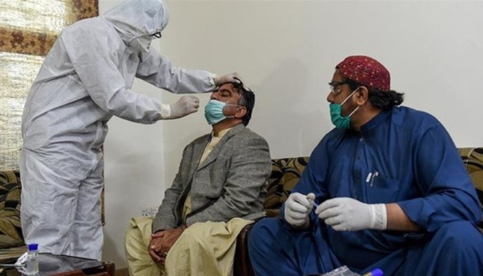 A health- worker takes a testing sample from a journalist during a nationwide lockdown over Covid-19 pandemic in Pakistan. Photo: AFP