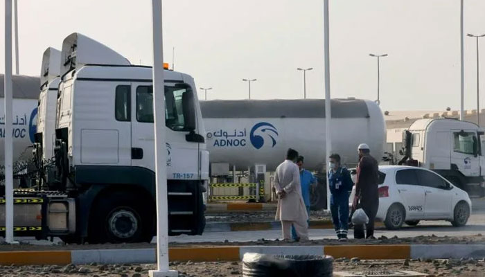 Men stand outside a storage facility of oil giant ADNOC in the capital of the United Arab Emirates, Abu Dhabi, on Monday, following an attack by Yemens Huthi rebels that ignited fuel tanks used by the company. AFP