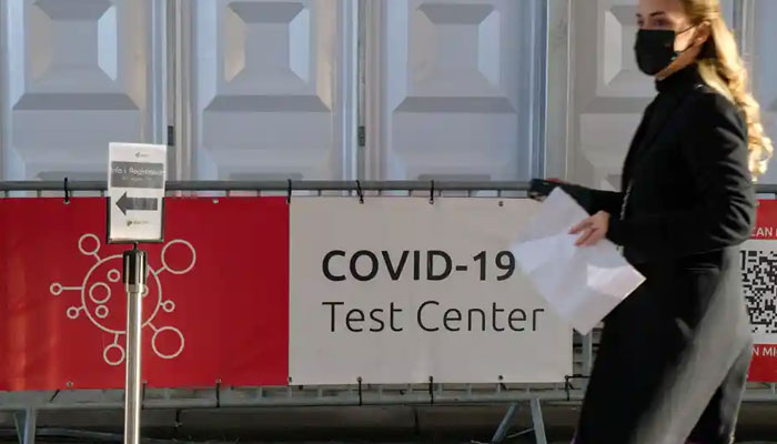 A woman in Brussels walks next to a Covid test centre. WHOs regional director for Europe is urging governments to act to halt the spread of Omicron. Agencies