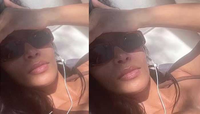 Kim Kardashian mendandani sosoknya yang terkenal dengan atasan hitam kecil saat dia berjemur di pantai