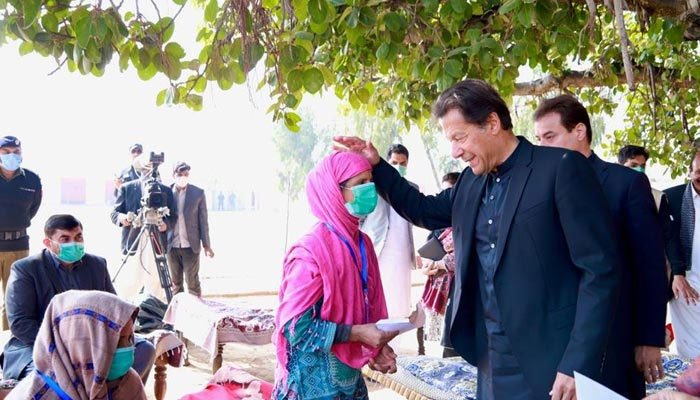 PM Imran Khan handing over aid to the citizens under a governments relief programme. Photo: Geo.tv/ file