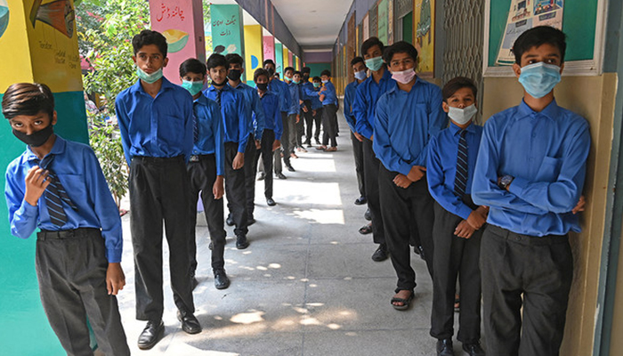 Students stand in queues as they wait for their turn to receive a dose of Pfizer vaccine against the Covid-19 coronavirus at a school in Lahore on October 1, 2021. — AFP/File