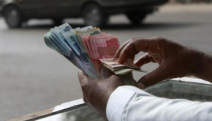 A dealer can be seen holding Pakistani currency. — Reuters/File