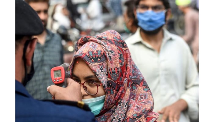 A shopping mall official (L) checks the body temperature of a customer for shopping ahead of Eid-ul-Fitr in Karachi. — AFP/File