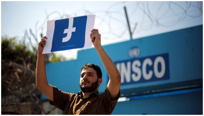 A Palestinian demonstrator holds a banner of the Facebook logo. Photo: AFP