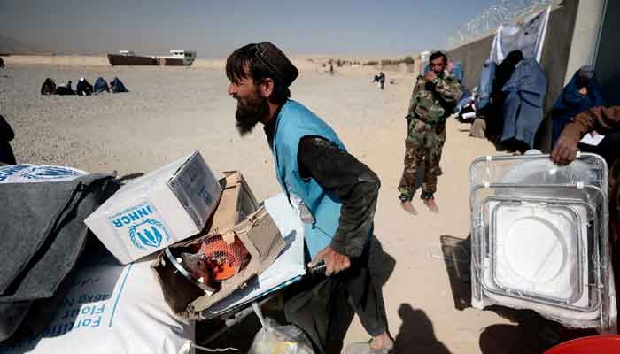 An UNHCR worker pushes a wheelbarrow loaded with aid supplies for a displaced Afghan family outside a distribution center as a Taliban fighter secures the area on the outskirts of Kabul, Afghanistan October 28, 2021. — Reuters/File