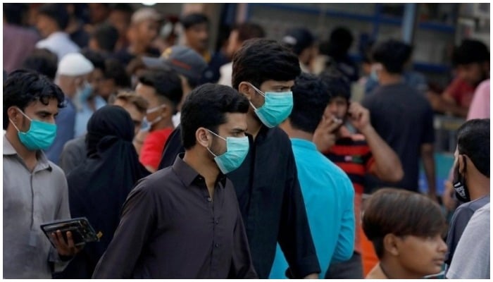 Men wearing masks walk in a crowded place. Photo: Reuters