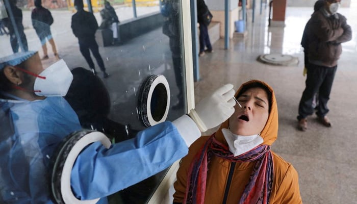 A healthcare worker collects a test swab sample from a woman amidst the spread of the coronavirus disease (COVID-19), at a testing centre inside a hospital in New Delhi, India, January 14, 2022. — Reuters