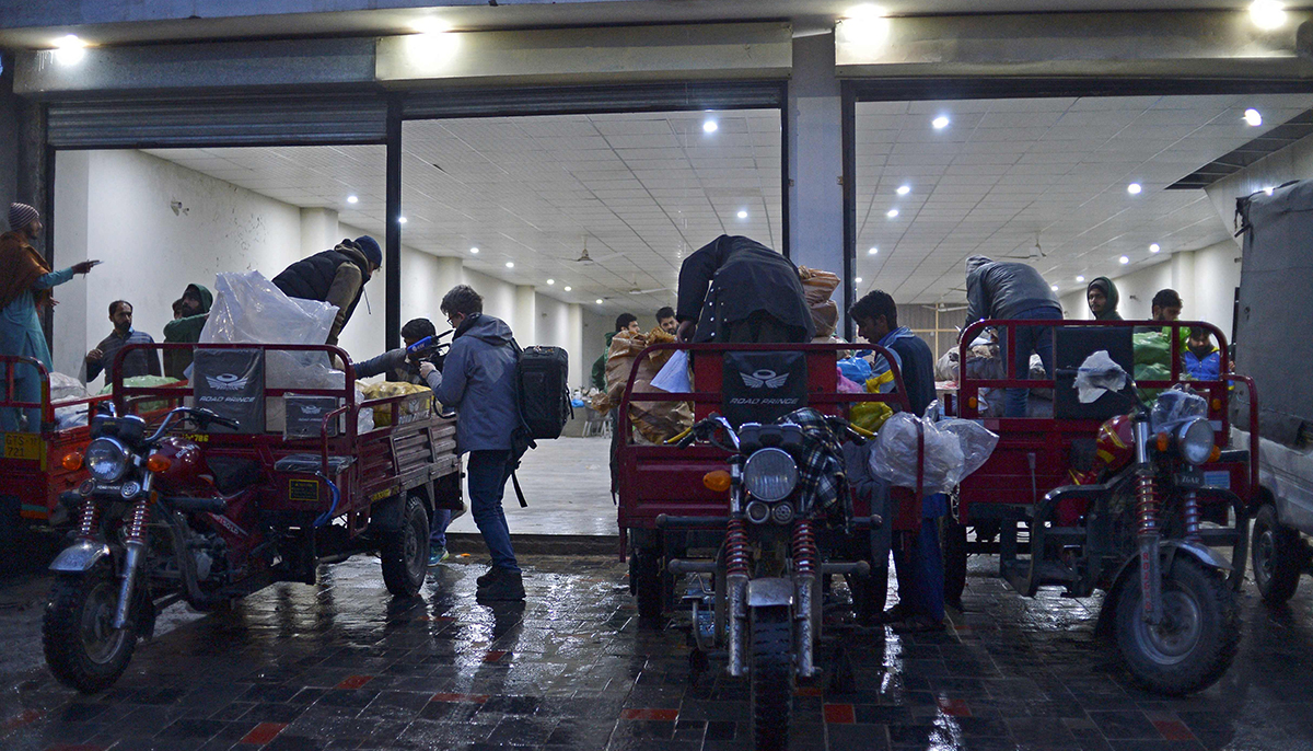 In this picture taken on January 8, 2022, workers of Taza Transforming Agriculture load vegetable bags on rickshaws at a distributing point in Lahore. — AFP