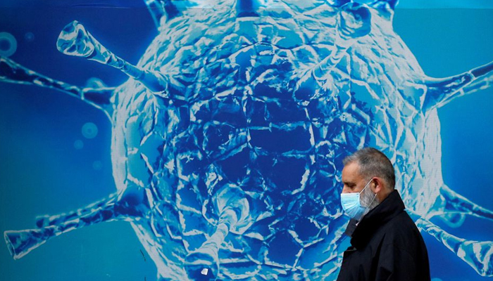 A man wearing a protective face mask walks past an illustration of a virus outside a regional science centre amid the coronavirus disease (COVID-19) outbreak, in Oldham, Britain August 3, 2020. — Reuters