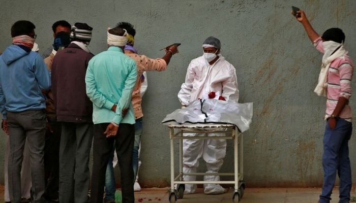 Men take photographs of the body of a relative after he died from the coronavirus disease (COVID-19) in Ahmedabad, India, January 24, 2022. Photo: REUTERS