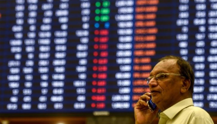 A investor can be seen speaking on phone in front of the digital board at the Pakistan Stock Exchange.— Reuters/File
