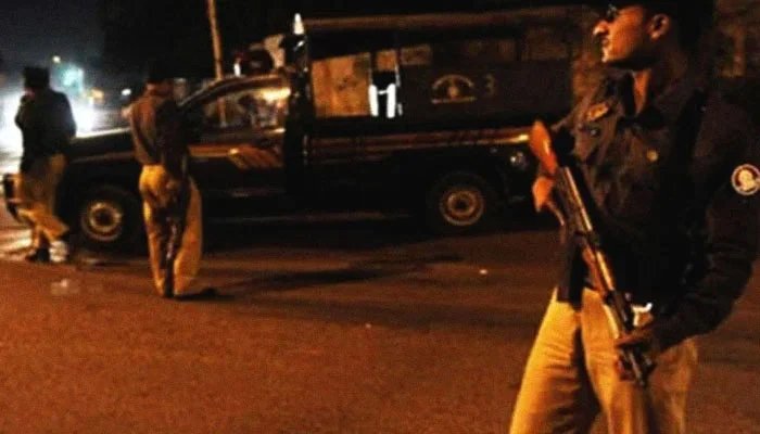 A cop stands holding a gun with a police van in the background. Photo: Geo.tv/ file