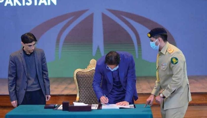 PM Imran Khan signs the public version of the national security policy. Photo — PM’s Office Twitter