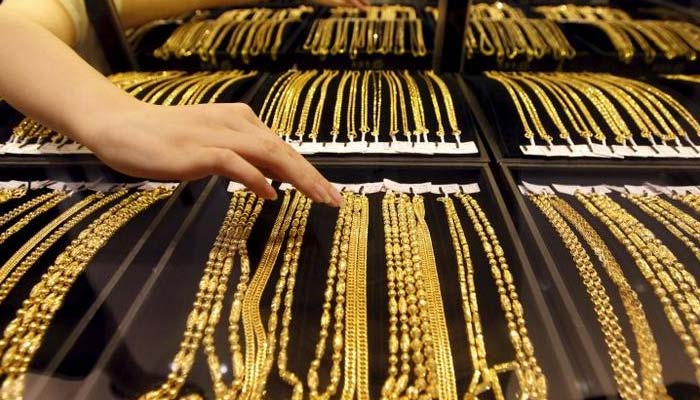 An employee arranges gold jewellery in the counter as her arm is reflected in the mirror at a gold shop in Wuhan, Hubei province, in August 25, 2011. — Reuters/File