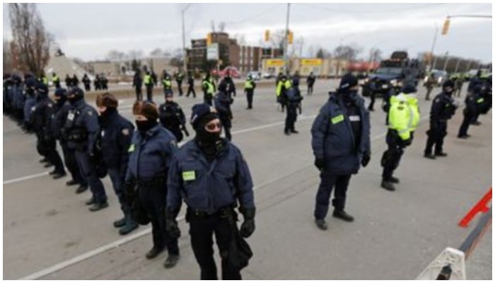 Police officers hold a line, on the road leading to the Ambassador Bridge, which connects Detroit and Windsor, after clearing demonstrators, during a protest against coronavirus disease (COVID-19) vaccine mandates, in Windsor, Ontario, Canada February 13, 2022. — Reuters/Carlos Osorio