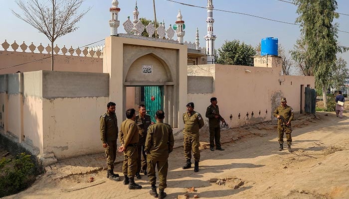 Police gather near the site where a man was killed after allegedly an angry mob stoned him to death at Khanewal district on February 13, 2022. — AFP