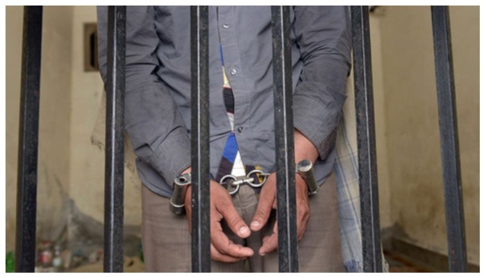 Man wearing handcuffs standing behind bars. For representation only — AFP