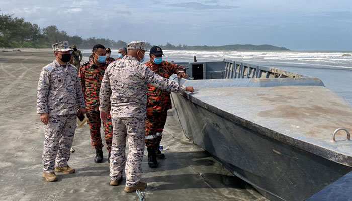 Officials inspect a boat that capsized and killed some of the people onboard, while other migrants remain missing in Kota Tinggi, Johor state, Malaysia on December 15, 2021. — Reuters/File