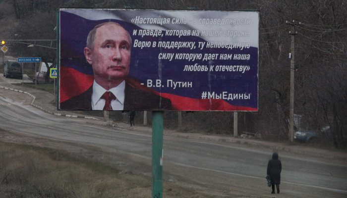 A woman walks past a billboard in support of Russian President Vladimir Putin in Simferopol, Crimea on March 3, 2022. The banner read The real strength is in justice and truth, which is on our side. I believe in support, invincible strength which our love for the Fatherland gives us. — AFP