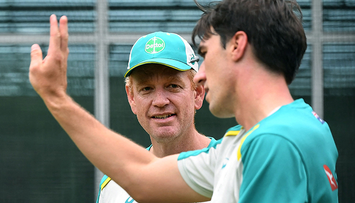Australian cricket captain Pat Cummins (R) speaks with coach Andrew McDonald (L) during their final practice session at the Melbourne Cricket Ground (MCG) in Melbourne on February 25, 2022. — AFP